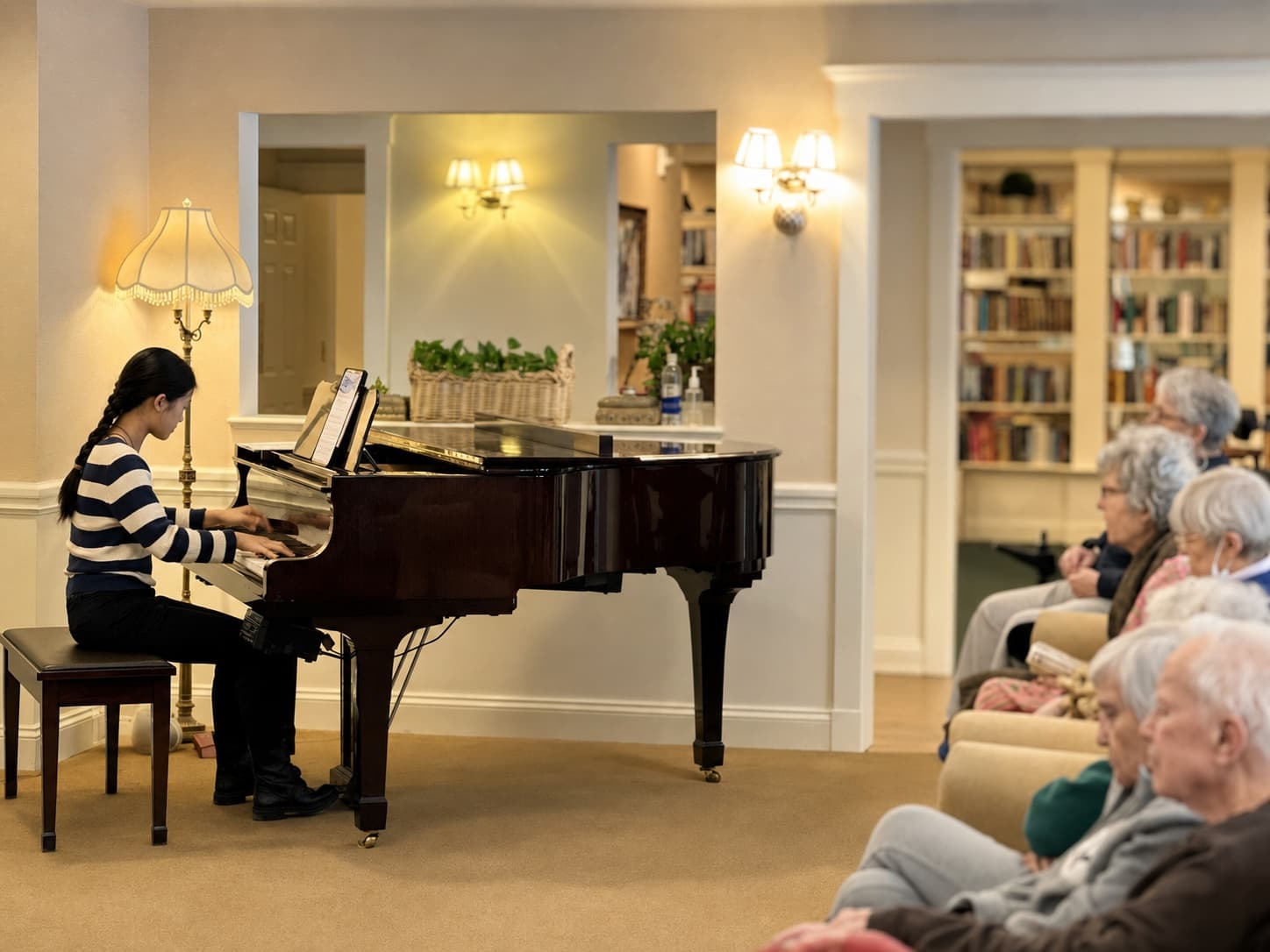 A young pianist performing for residents in a senior community
